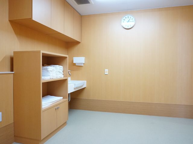 清潔な居室 浴室 シンプルで清潔感のある居室です。白い壁時計が時間を教え、整理されたタオルが備え付けの棚に準備されています。