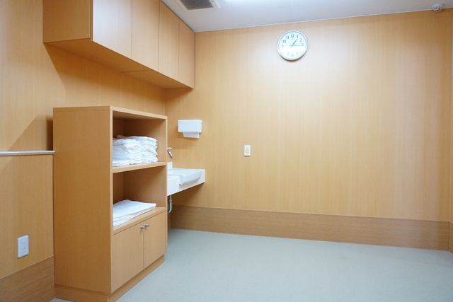 清潔な居室 浴室 シンプルで清潔感のある居室です。白い壁時計が時間を教え、整理されたタオルが備え付けの棚に準備されています。
