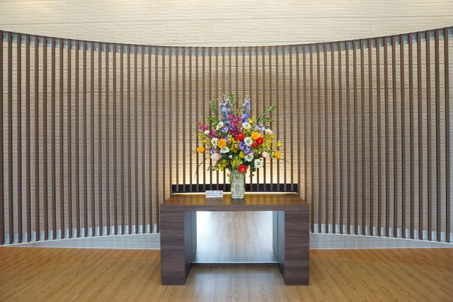 花瓶とテーブルのあるスペース 展示物 落ち着いた雰囲気の中で、色とりどりの花が飾られたテーブルがお出迎えします。憩いの時間をより豊かにする空間です。