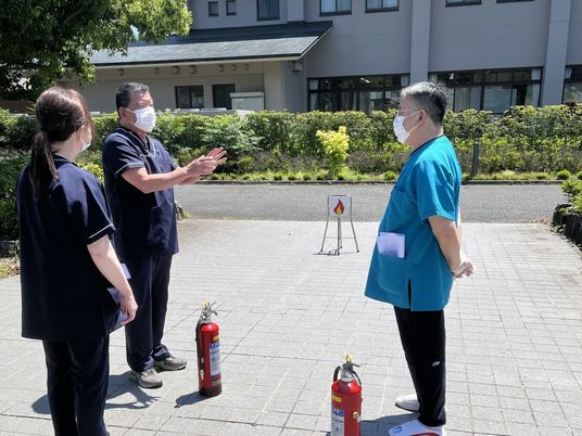 屋外で避難訓練をする職員  