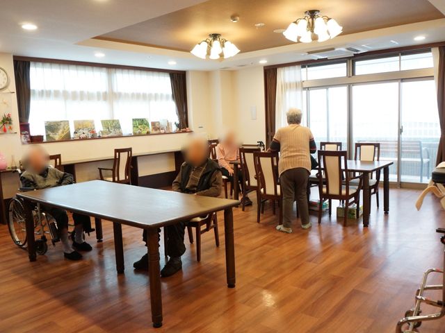 和やかな休憩スペース 食堂 広々としたダイニングで、利用者様が談笑されており、コミュニケーションも活発です。窓からは陽光が差し込み、温もりを感じる場所となっています。