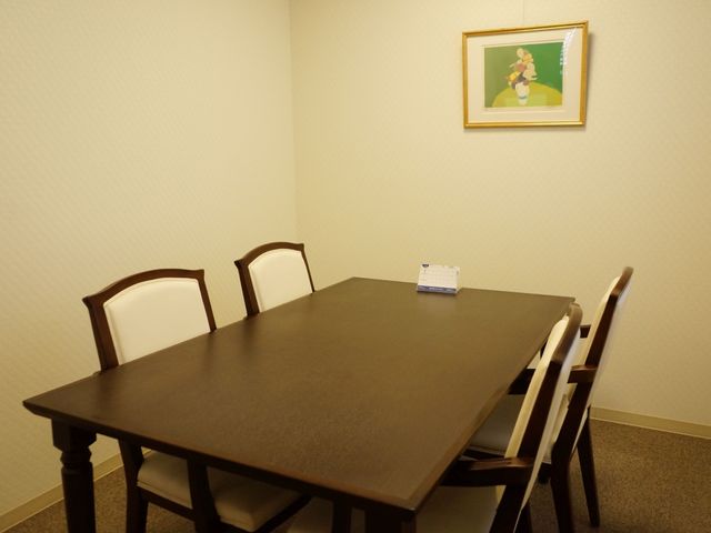 シンプルな居室のテーブル 相談室 落ち着いた色合いの居室は、ゆったりとした時間を過ごせる仕様になっています。採用を検討中の方にとって、快適な労働環境が期待できます。