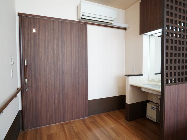 洗面台と扉のある居室 居室 ゆとりのある居室には広々とした洗面台が備わっており、日々の準備がしやすい造りです。扉の取っ手も安全に配慮されています。