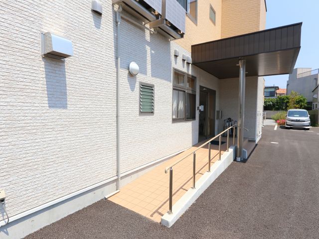 明るい外観の入り口部分 玄関先 手すりが設置された安全で明るいエントランスです。心地よい風が通る開放感のある空間で、訪れる皆様を温かく迎えます。