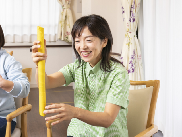 笑顔の職員とリハビリ活動 穏やかな雰囲気の中で、職員が優しくリハビリを支援しています。利用者様と共に明るい笑顔が印象的な空間です。