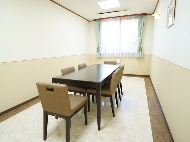 清潔な食堂の居室 共有スペース この空間では食事の時間を共に過ごし、コミュニケーションも楽しめます。日差しの入る窓際で、心地よいひと時をお過ごしください。