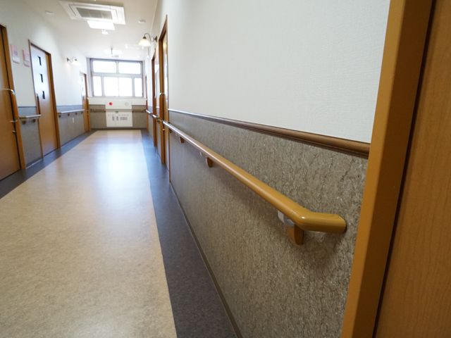 廊下に設置された手すり 廊下 床面が清潔で明るく、手すりも設置された廊下です。スタッフとして安全にご高齢者をサポートできる環境が整っています。