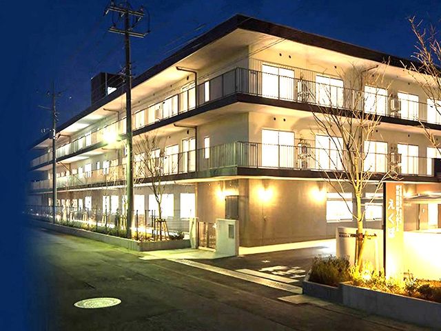夜の施設外観 外観   夜でも室内の明かりがよく見える三階建ての建物です。バルコニー付きで、落ち着いた雰囲気の職場をイメージしやすいです。