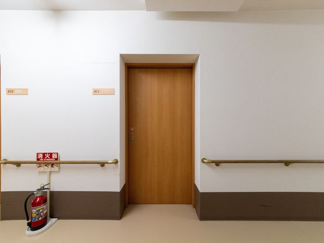 廊下の居室前 廊下   木目の扉が並ぶ落ち着いた廊下です。手すりが設置され、移動しやすい環境になっています。