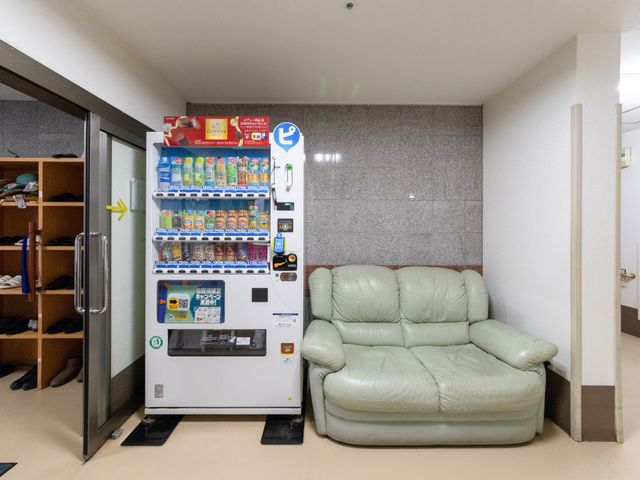 休憩用ソファと自販機のある休憩室 休憩室   自販機とソファが置かれた休憩しやすい空間です。更衣用の棚も見え、職員の合間のひと息に使いやすそうです。