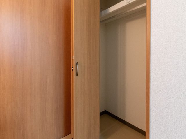 開いたクローゼット 居室   木目調の扉が付いたクローゼットで、落ち着いた雰囲気です。居室の収納がしっかり確保されており、整理しやすそうです。