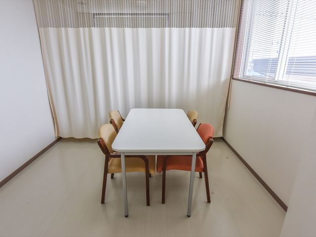 清潔な居室のテーブルと椅子 相談室 シンプルで清潔感のある居室です。窓からの自然光が心地よい空間で、ゆったりと過ごすことができます。