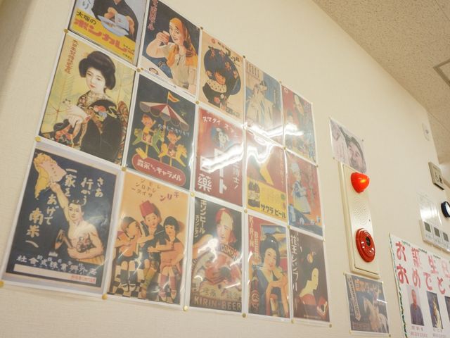 レトロな掲示物の壁面 掲示物  懐かしい雰囲気の広告ポスターが壁に飾られ、訪れる人々に心和む空間を提供しています。