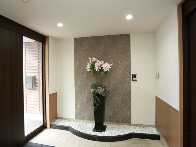 エントランスの花とインテリア 入口 温かみのあるエントランスが迎えてくれます。訪れる人々に安らぎを提供する、洗練された空間がここにあります。