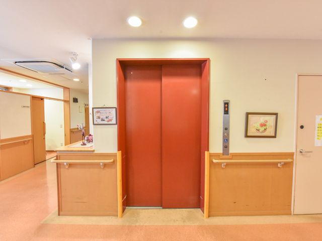 赤い扉のエレベーター エレベーター前 ゆったりとした空間のエレベーター前です。明るく清潔感のある廊下は、安心してご利用いただけるようになっています。