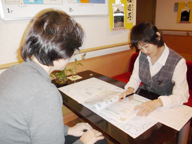 利用者と相談する職員 スタッフイメージ 職員が丁寧に対応しながら、明確な説明を提供している様子です。安心して日々を過ごせる環境が整っています。