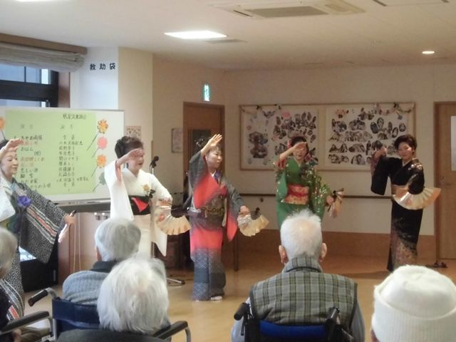 踊りのパフォーマンス居室 居室 居室では入居者の前で色鮮やかな衣装を纏った方々が踊りを披露しています。和やかな雰囲気が漂っています。