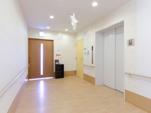 明るく清潔な廊下 エレベーターホール 手すりが設けられた廊下は、ゆったりとして清潔感があります。通行のために工夫が凝らされ、快適な移動が支援される空間です。