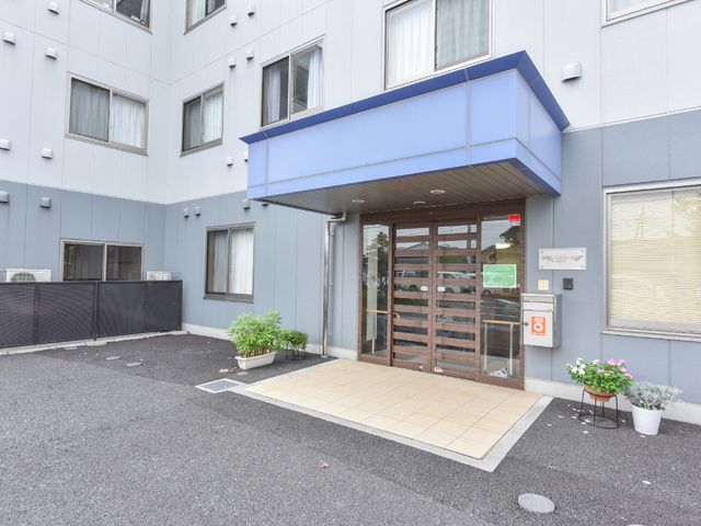 清潔な施設のエントランス 入り口 落ち着いた色合いのエントランスがお出迎え。木目調のドアが温かみを感じさせ、訪れる皆さまを優しく迎え入れます。
