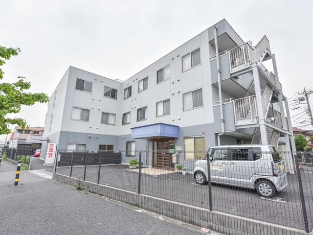 青い屋根の白い建物 道路 清潔感のある外観で、白と青の色合いが印象的です。スタッフとして、こちらの環境で働くことをご検討ください。