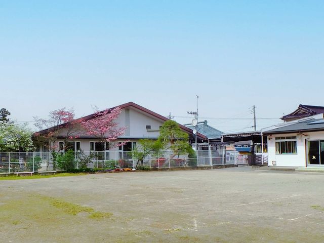施設の外観と庭先 外観   広い敷地に建物がゆったり配置され、前面には木々や花壇が見えます。落ち着いた環境で働く様子をイメージしやすい外観です。