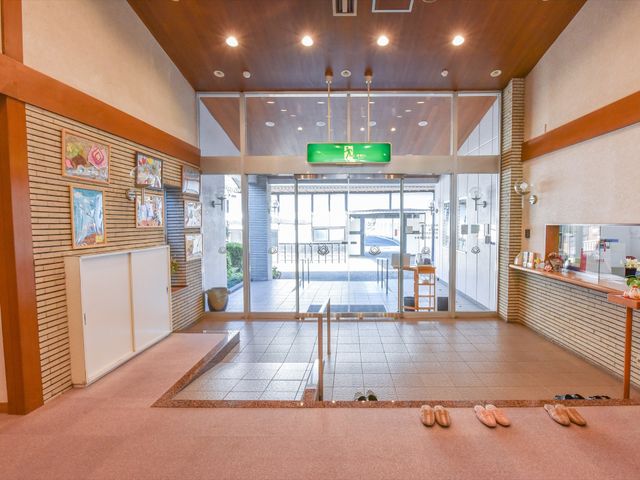 明るいエントランスの様子 玄関 温かみのあるロビーがお出迎えします。スリッパが整然と並び、訪れる方々を心地よくお迎えする空間です。