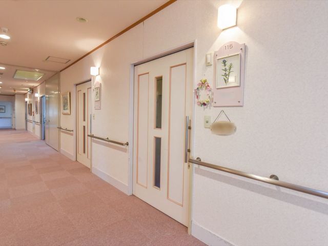 清潔感ある廊下 通路 手すり沿いの落ち着いた色合いの廊下が、安心して歩ける空間を提供しており、訪れた方を温かくお迎えします。
