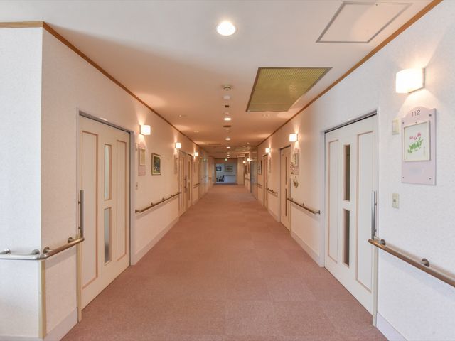 廊下の清潔な空間 通路 ゆとりのある通路がゆっくりとした時間を過ごす方々を優しく包み込んでいます。壁には落ち着きのあるアートが飾られ、温かみのある雰囲気を演出しています。
