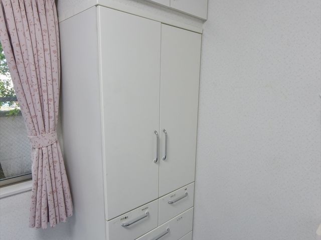 白い壁に置かれた収納家具 収納 整理された居室の収納家具は、使いやすさを考慮したデザインです。ユーザーの私物を整頓するための充分なスペースがあります。