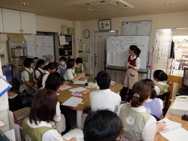 職員研修の様子が見える多目的室 多目的室   職員の方々が集まり、白板を使って説明を受けています。打ち合わせや研修に使いやすい、落ち着いた空間です。
