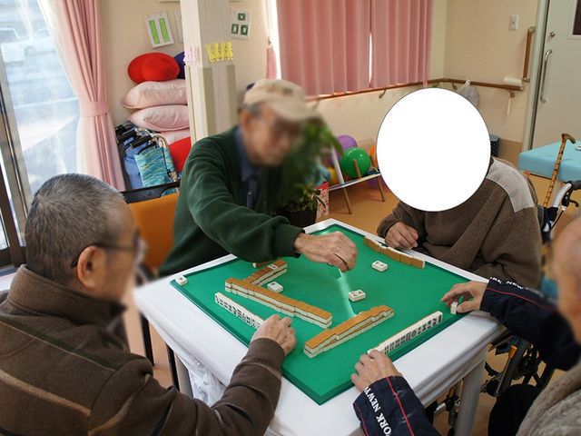 ゲームを楽しむ人々の部屋 多目的室 自然光が射し込む明るい空間で、椅子に座りながら皆で楽しくゲームを楽しんでいます。