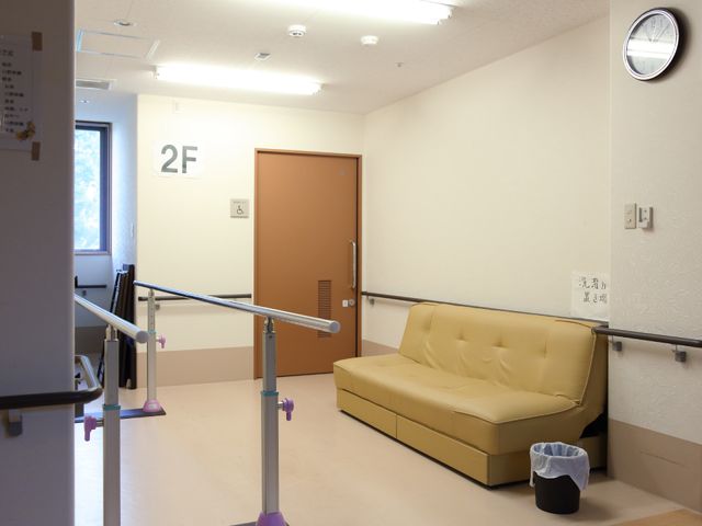 廊下のソファと手すり 部屋 明るく清潔な休憩スペースが配された廊下です。休憩時間に柔らかなソファで一息つける環境が整っています。