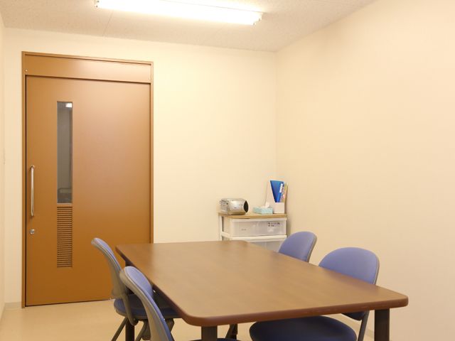 シンプルな休憩室の一角 談話ルーム ゆったりとした時間を過ごせる休憩室の角に設けられたテーブルと椅子。個々のリラックスタイムや小さな会議にも最適です。