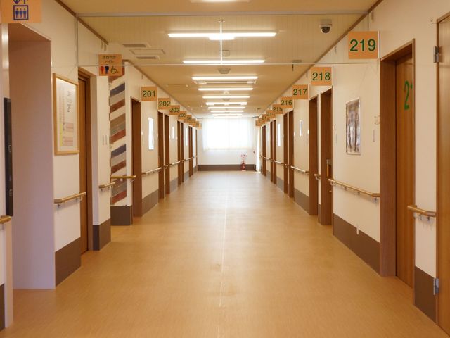 明るく清潔な廊下 通路 ゆとりのある廊下は、清掃が行き届いており、清潔感が感じられます。白い壁と木の扉が、暖かみのある雰囲気を醸し出しています。