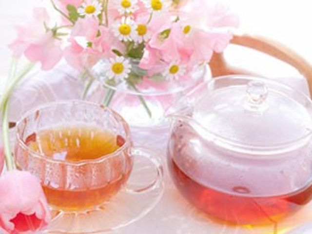 ティーセットのテーブル スタッフイメージ 色とりどりのお花と紅茶でリラックスする時間を過ごせる場面です。施設における和やかなひとときです。