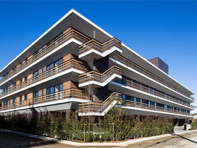 モダンな外観の建物 外観   青空に映える、バルコニーが重なるモダンな建物です。周囲に植栽があり、落ち着いた印象です。