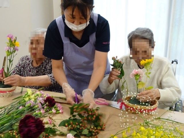 花を活ける様子の多目的室 多目的室 手に花を持ちながら、活き活きとした表情で花を活ける様子が見られます。皆さまで色鮮やかな花に触れながら、心豊かな時間を過ごされています。