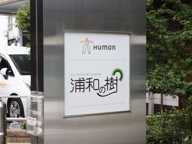 施設の名称が記された看板 清潔感あふれる施設の入口にて、笑顔でのお出迎えを大切にしています。職員一同、あたたかな対応を心がけております。