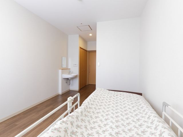 明るく清潔な居室 居室 シンプルで落ち着いた雰囲気の個室です。必要最低限の家具としてベッドと洗面台が備え付けられており、ゆったりとお過ごしいただけます。