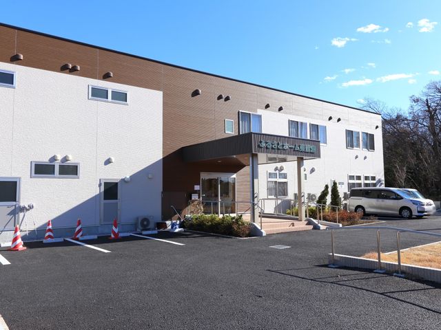 明るい日差しのエントランス 外観 庭木が整えられ、澄み切った空の下、歓迎する雰囲気のエントランス。訪れる皆さんに安らぎを提供しています。