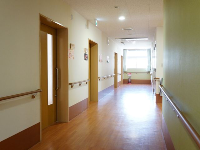 清潔な廊下の風景 廊下 手すりが設置された明るい廊下は、安全かつ快適にご移動いただける設計です。ゆったりとした空間が、落ち着いた時間をお過ごしいただくために整えられています。