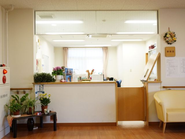 明るい受付のある空間 事務室 清潔感のあふれるフロントで、暖かな雰囲気にお出迎えいたします。華やかな花や観葉植物が、訪れる人々の心を和ませています。