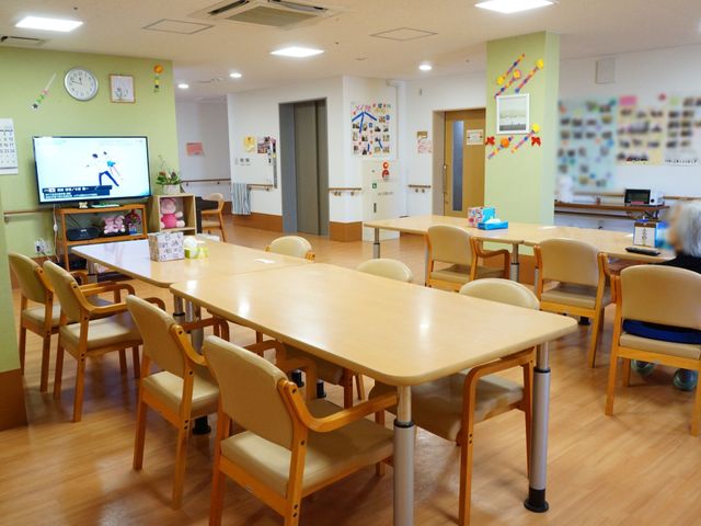 カラフルな壁の食堂 食堂 広々とした食堂にはテーブルと椅子が整然と配置され、温かみのある空間で交流を深めることができます。壁に掲示された工作品が明るい雰囲気を作り出しています。