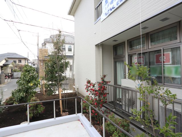 明るい外観の施設入口 植え込み 植栽に囲まれた清潔感のあるエントランスで、来訪者を暖かく迎えます。住宅街に溶け込む落ち着いたデザインが特長です。