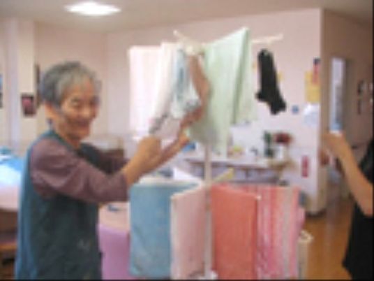 笑顔で洗濯物を畳む高齢者