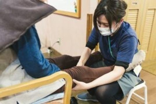 利用者の足に手を当てるスタッフ