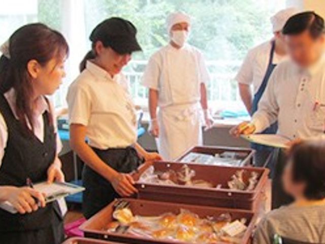 食事の準備風景 食堂 スタッフが食事を提供し、明るい雰囲気の中で入居者との交流が見られます。