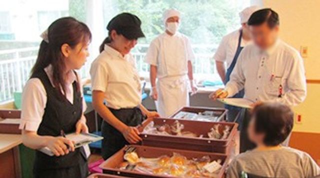 食事の準備風景 食堂 スタッフが食事を提供し、明るい雰囲気の中で入居者との交流が見られます。