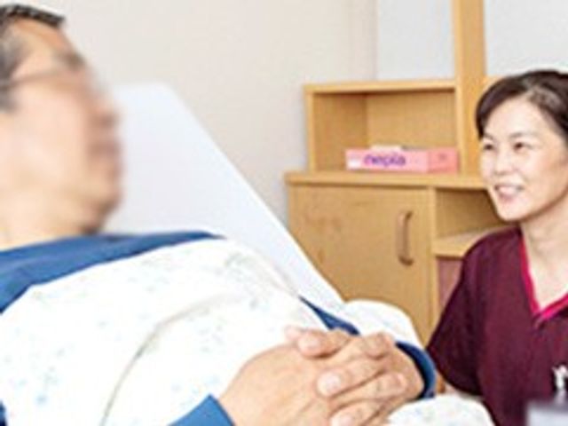 スタッフと入居者の様子 居室 スタッフが居室で入居者に寄り添い、穏やかな時間を過ごしています。温かい雰囲気が感じられます。