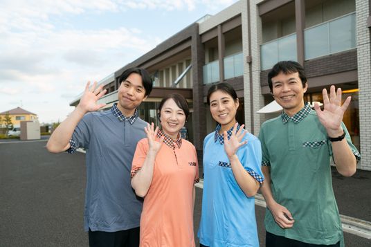 笑顔の職員が外で挨拶する外観  